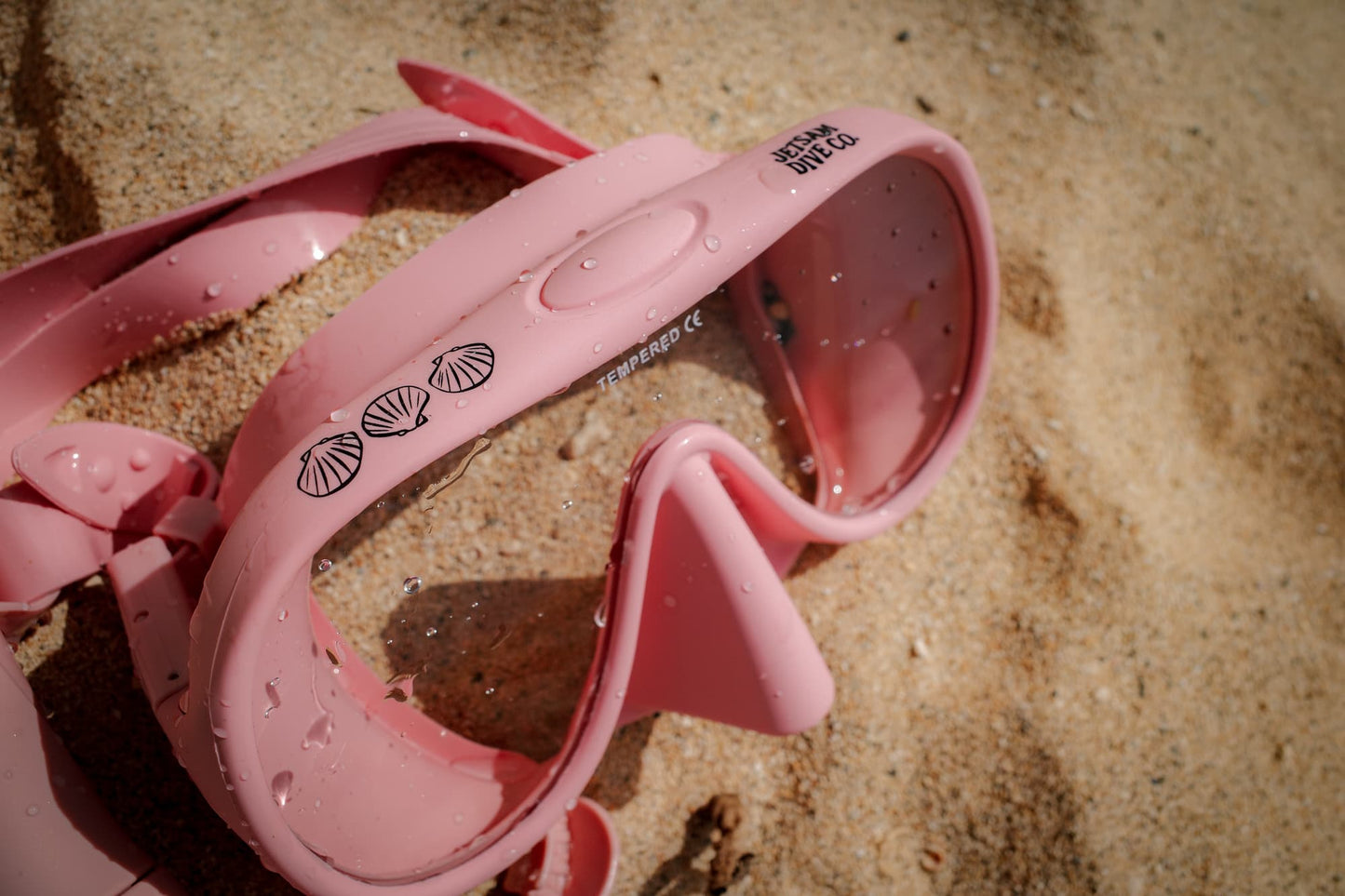 Pink dive mask on a sandy surface