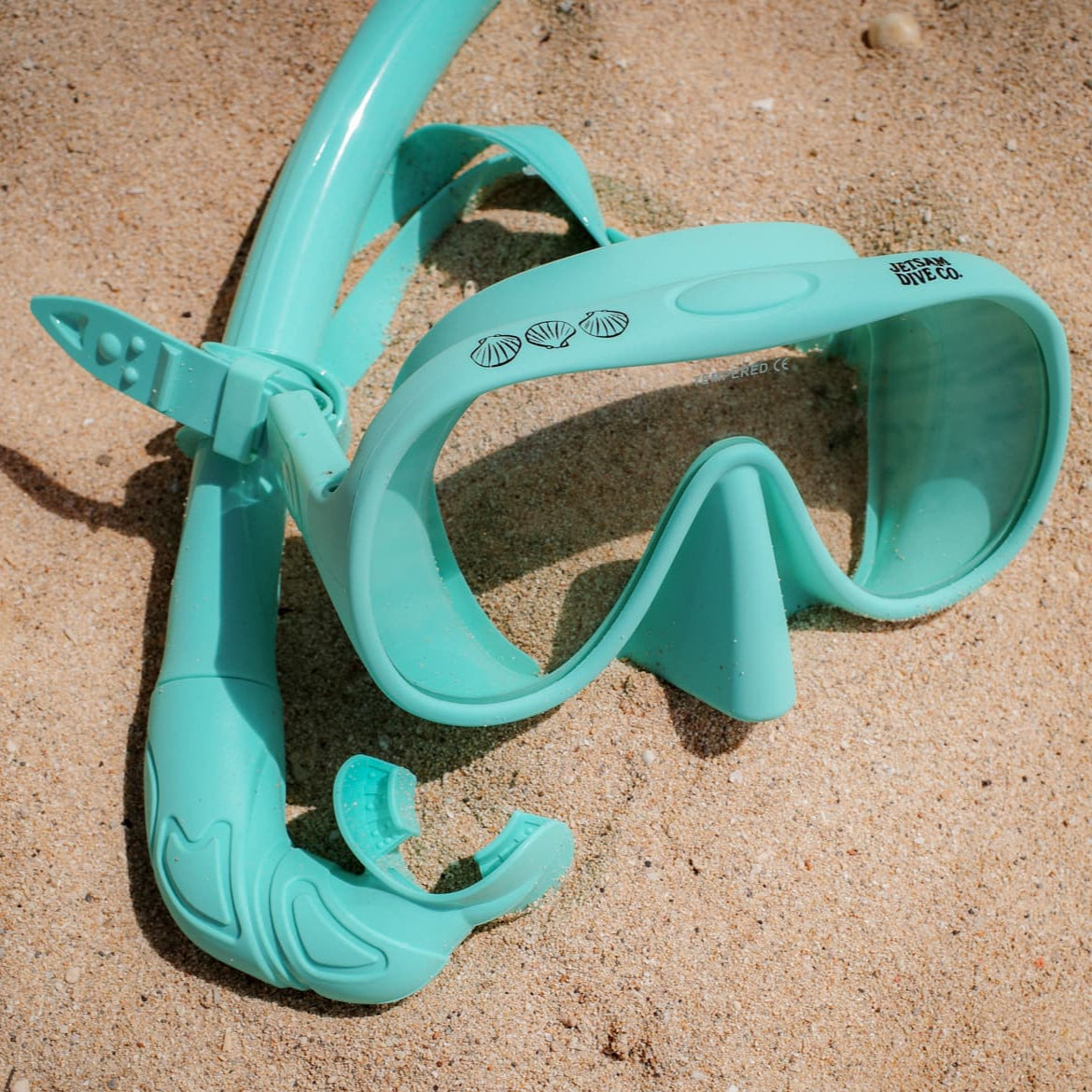 Turquoise dive mask on sandy surface