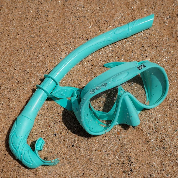 Turquoise snorkel and mask set on sandy ground