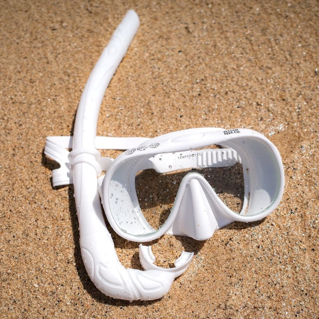 White snorkel and mask set on sandy ground