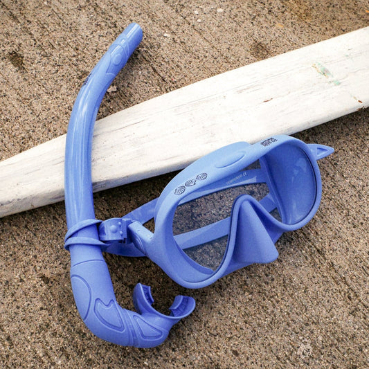 Blue snorkel mask and gray paddle on a concrete surface