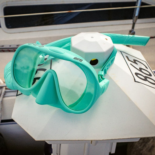 Turquoise diving mask on a white float with a boat in the background